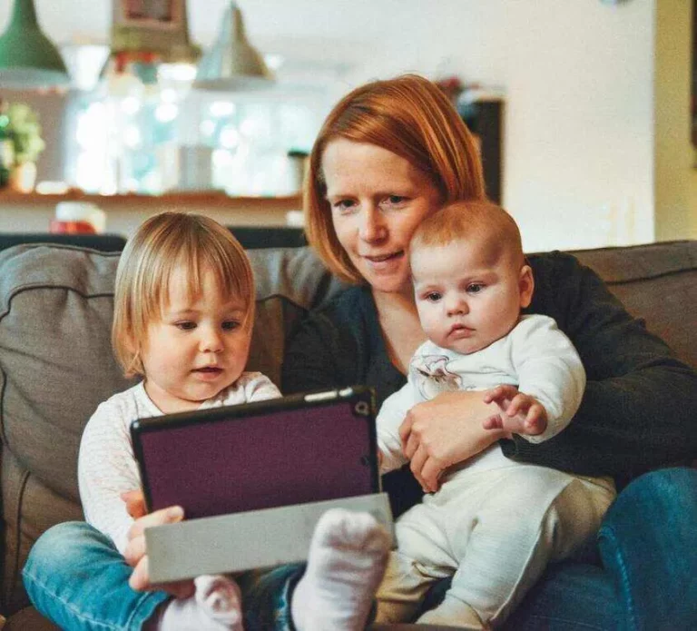 Mutter mit 2 Kindern in der Hand und einem Laptop