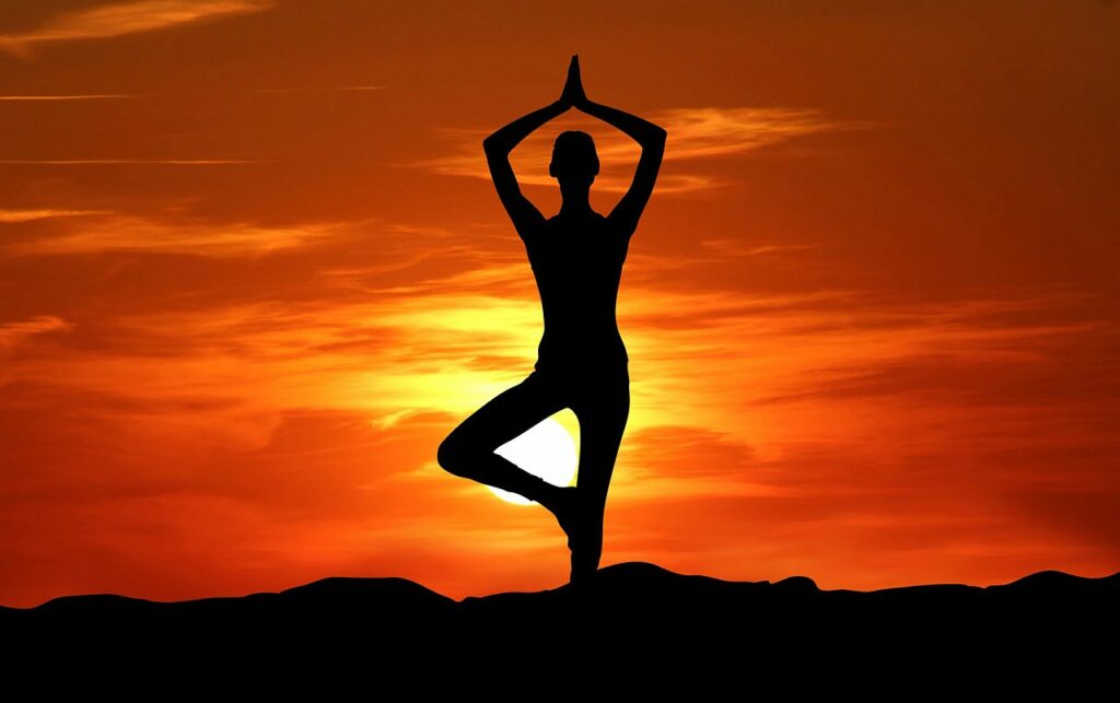 Eine Silhouette von einer Person in Yoga Stellung in Abendrot