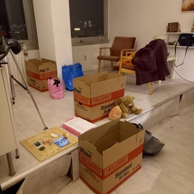 Ein Zimmer, in der Umzugskartons herumstehen. Das Zimmer wirkt unordentlich.